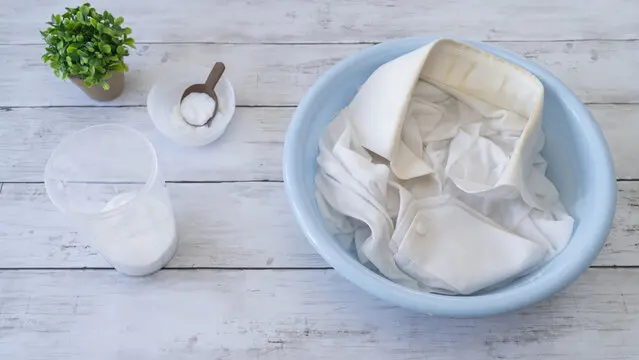 洗面器に入れられた洗濯物と粉状の洗浄剤